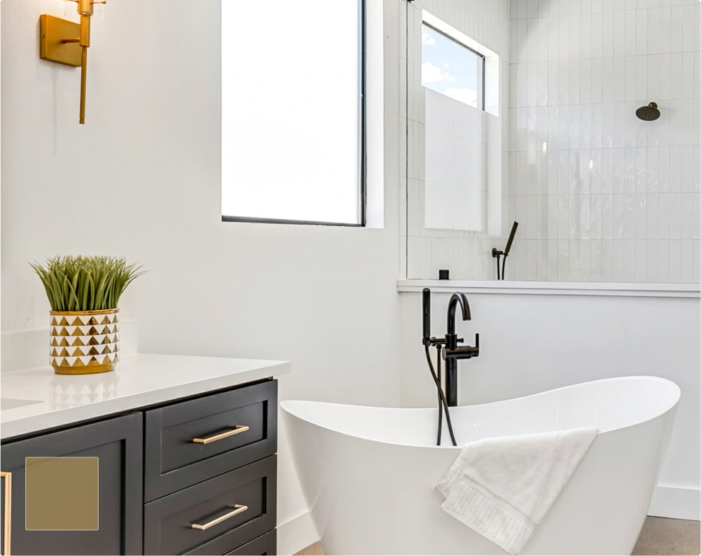 Modern bathroom with freestanding white tub, black faucet, gray vanity with gold handles, and glass shower partition.